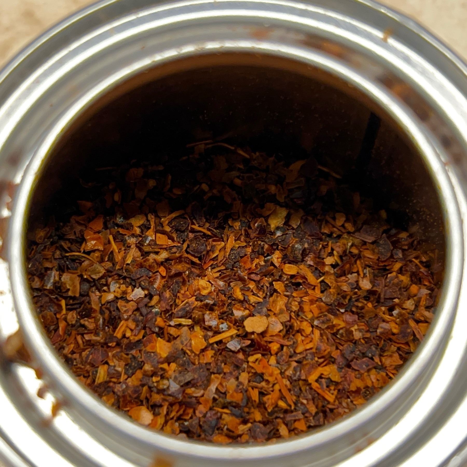 Flakes of paprika in a silver metal container. 