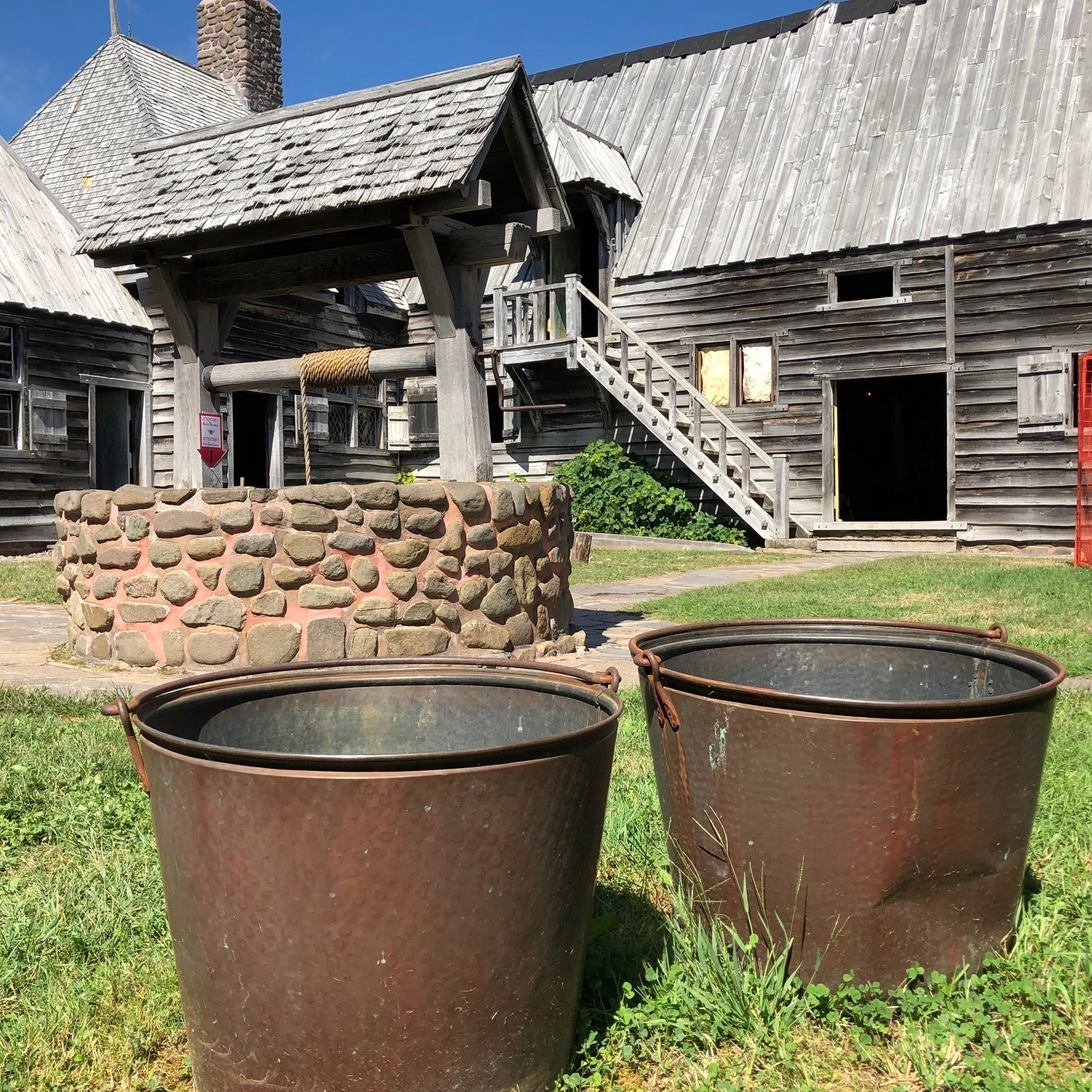 Two metal buckets and well in courtyard of historical settlement.