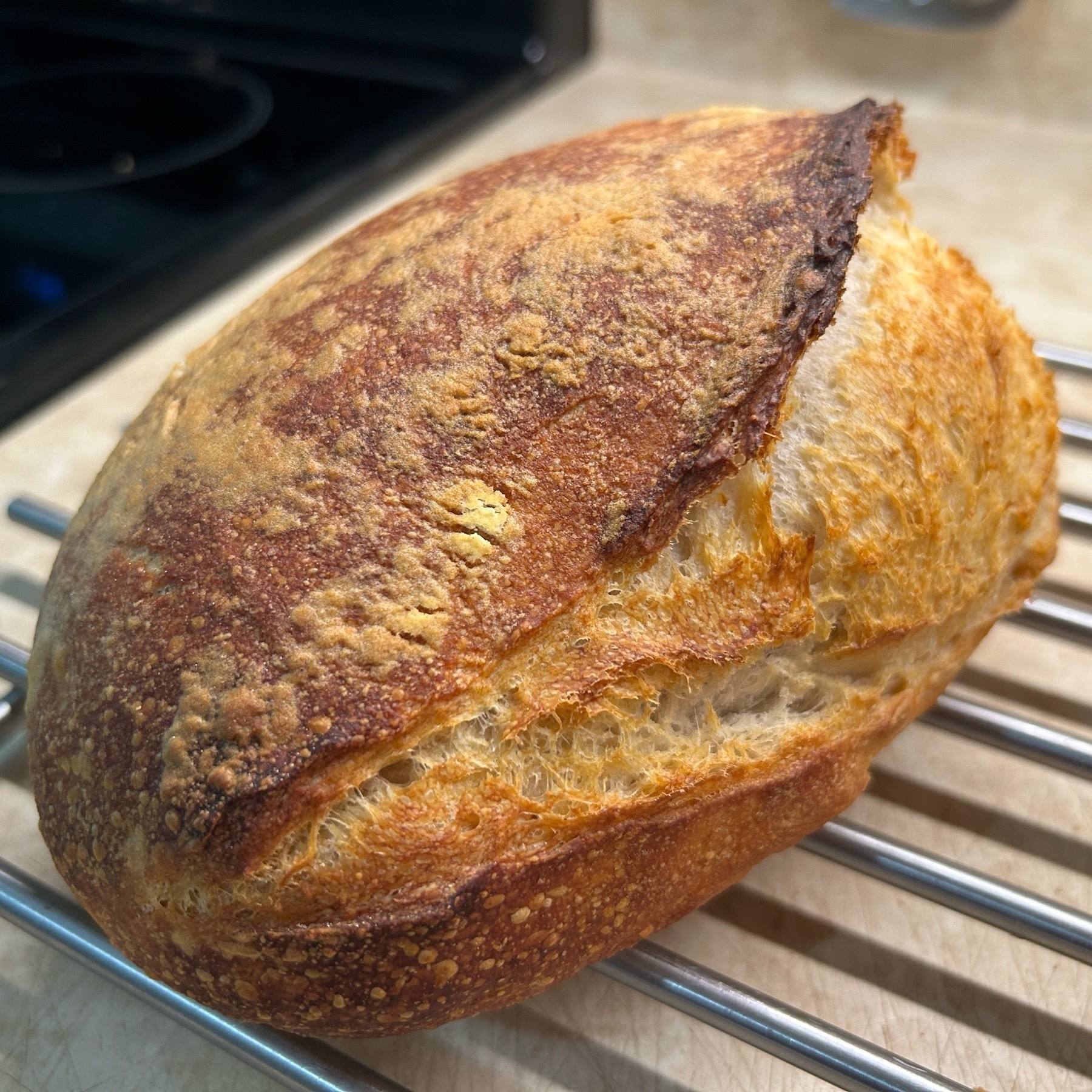 Load of rustic sourdough bread with a large slash across it where the loaf expanded during baking. 