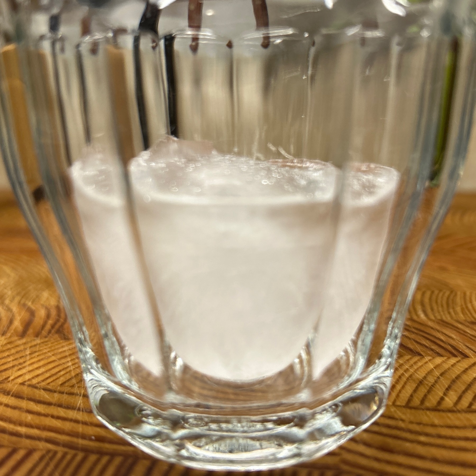 Small glass with round ice cube visible in it. 