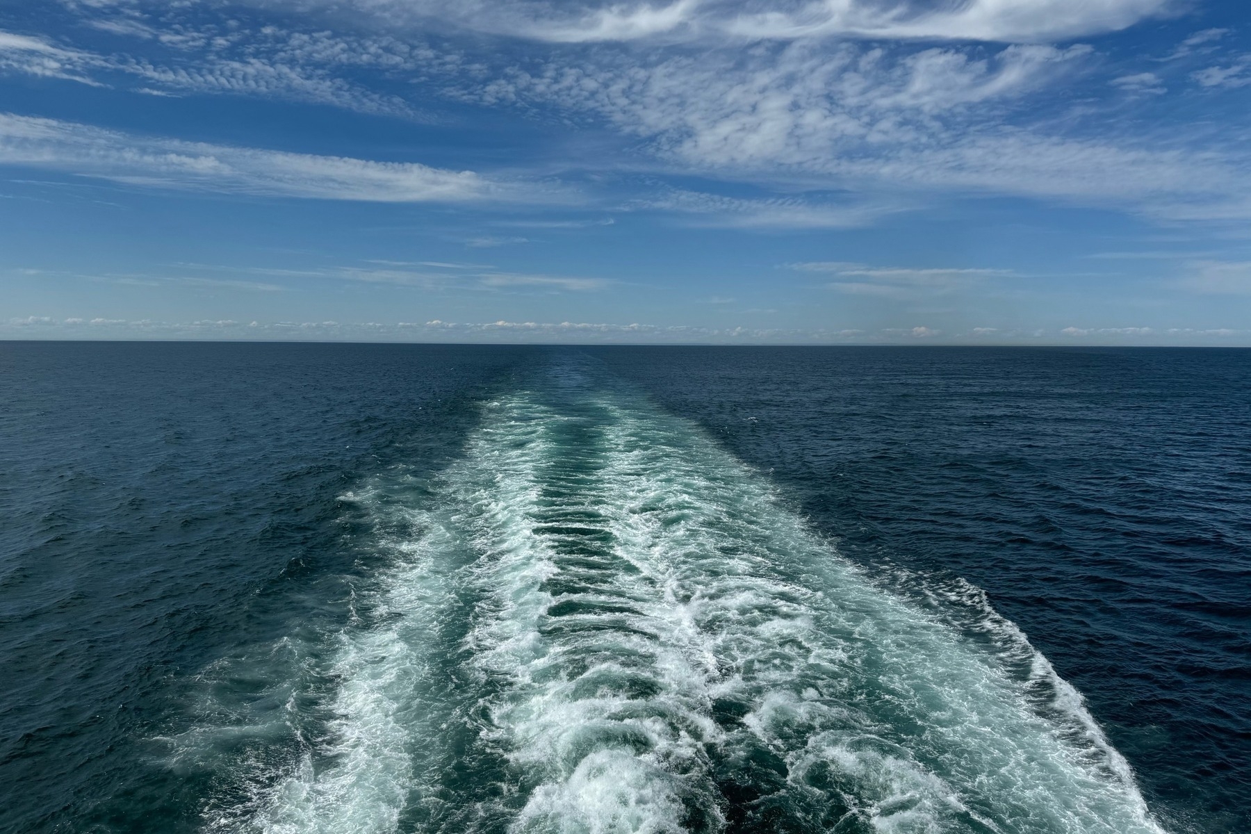 Wake of a ferry with a cloudy sky above. 