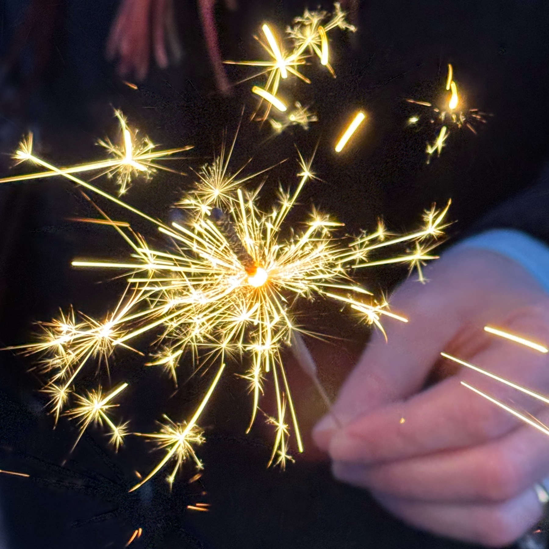 Sparks from a sparkler held in someone's hand. 