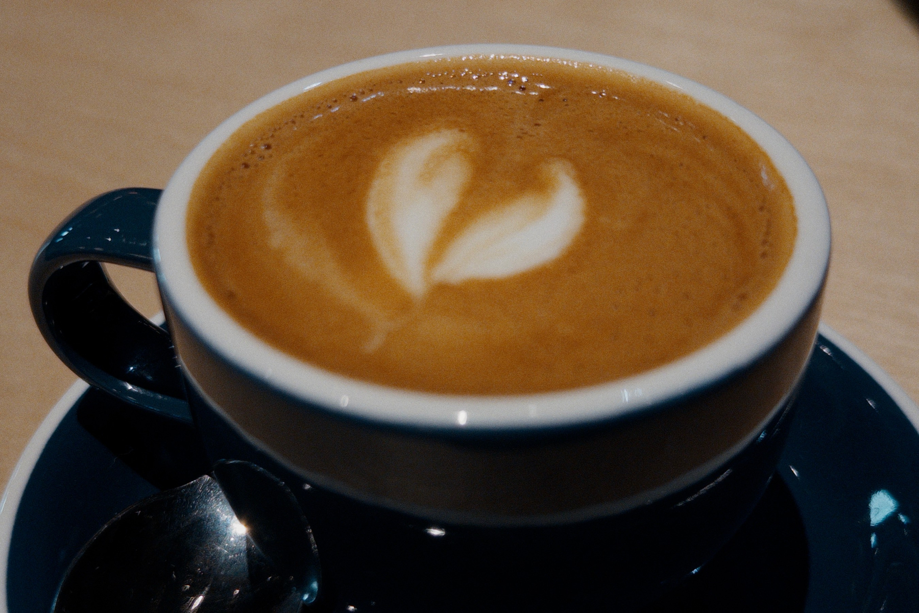 Espresso macchiato with foam and heart shape design in a dark blue cup. 