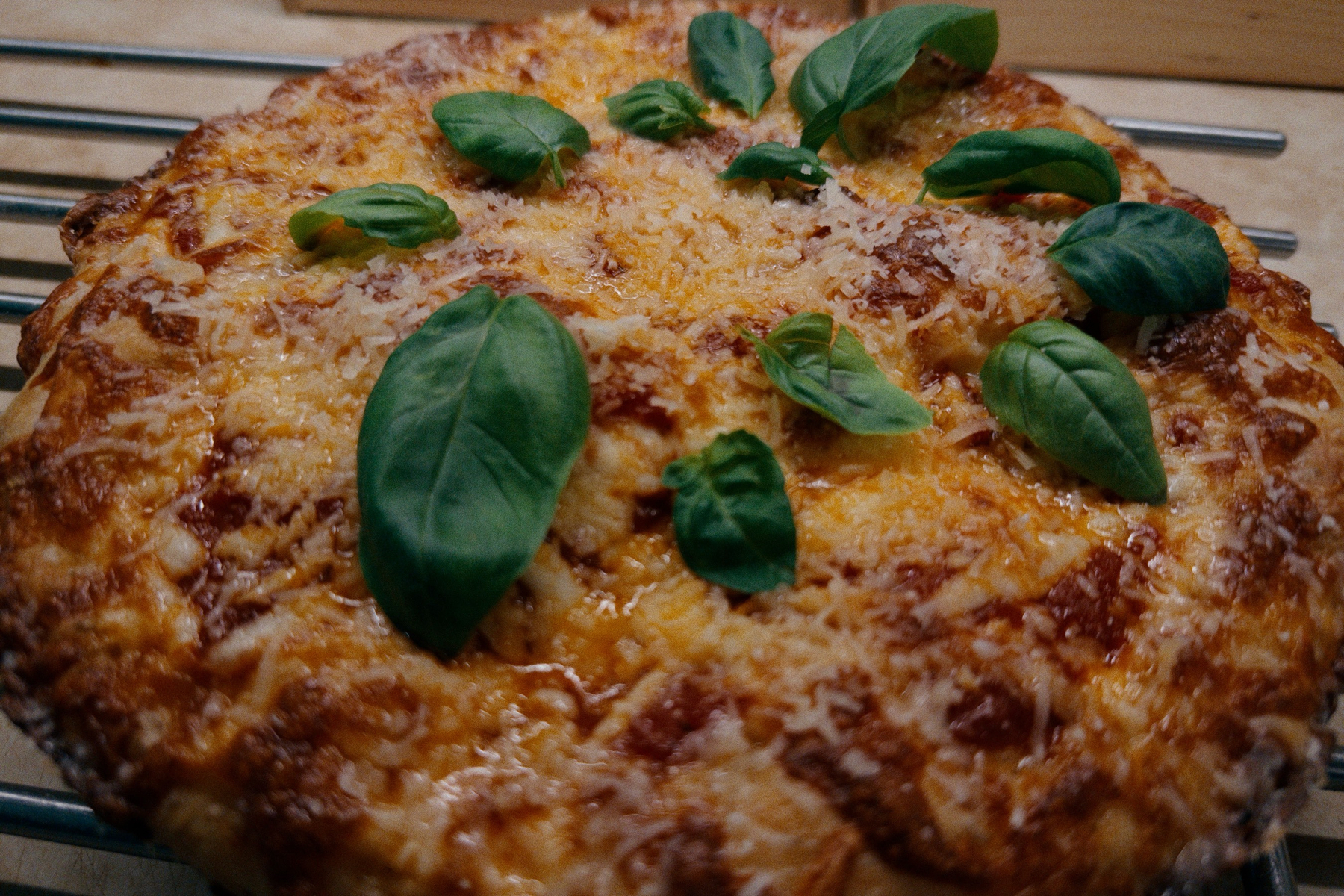 Surface of deep dish pizza with melted cheese, tomato sauce, and basil leaves. 