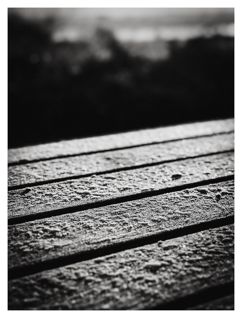 Outdoor table with ice on the wood, in black and white. 