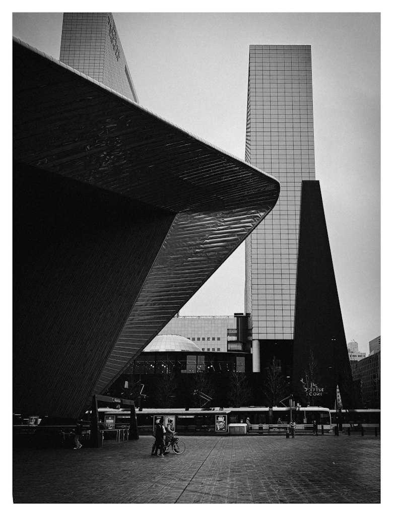 Black and white photo of the iconic Rotterdam Central station building and the office towers next to it. 