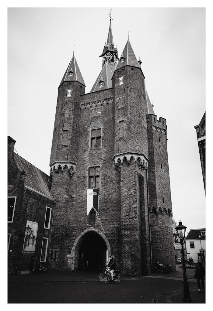 The “Sassenpoort” in Zwolle, with a cyclist in front cycling by. In black and white. 