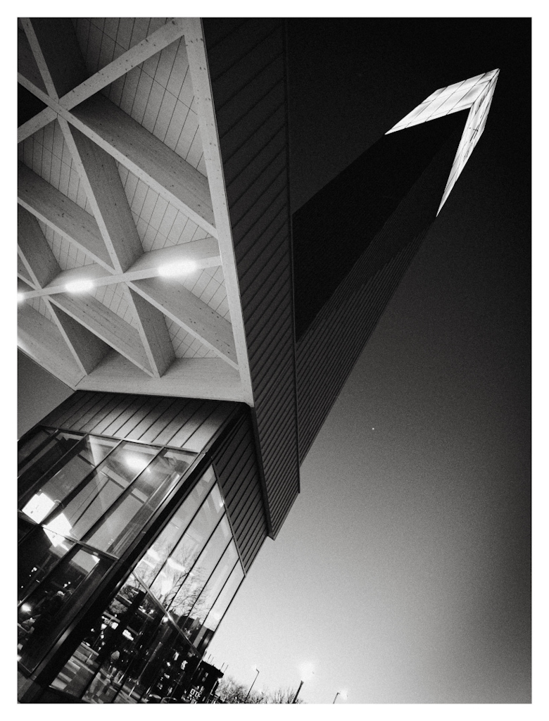 Diagonal lines of a modern train station building disappearing in the night sky (black and white)