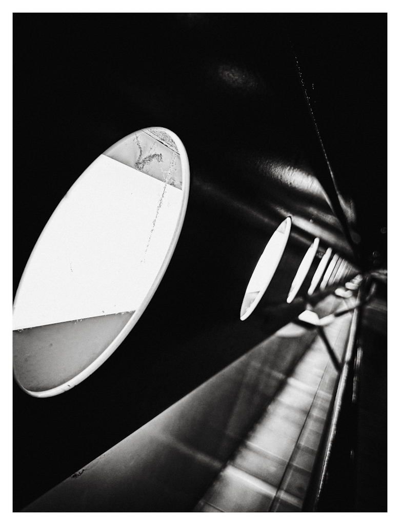 A rail with circle shaped openings, lighted from behind, diagonally leading away in the darkness. In black and white. 