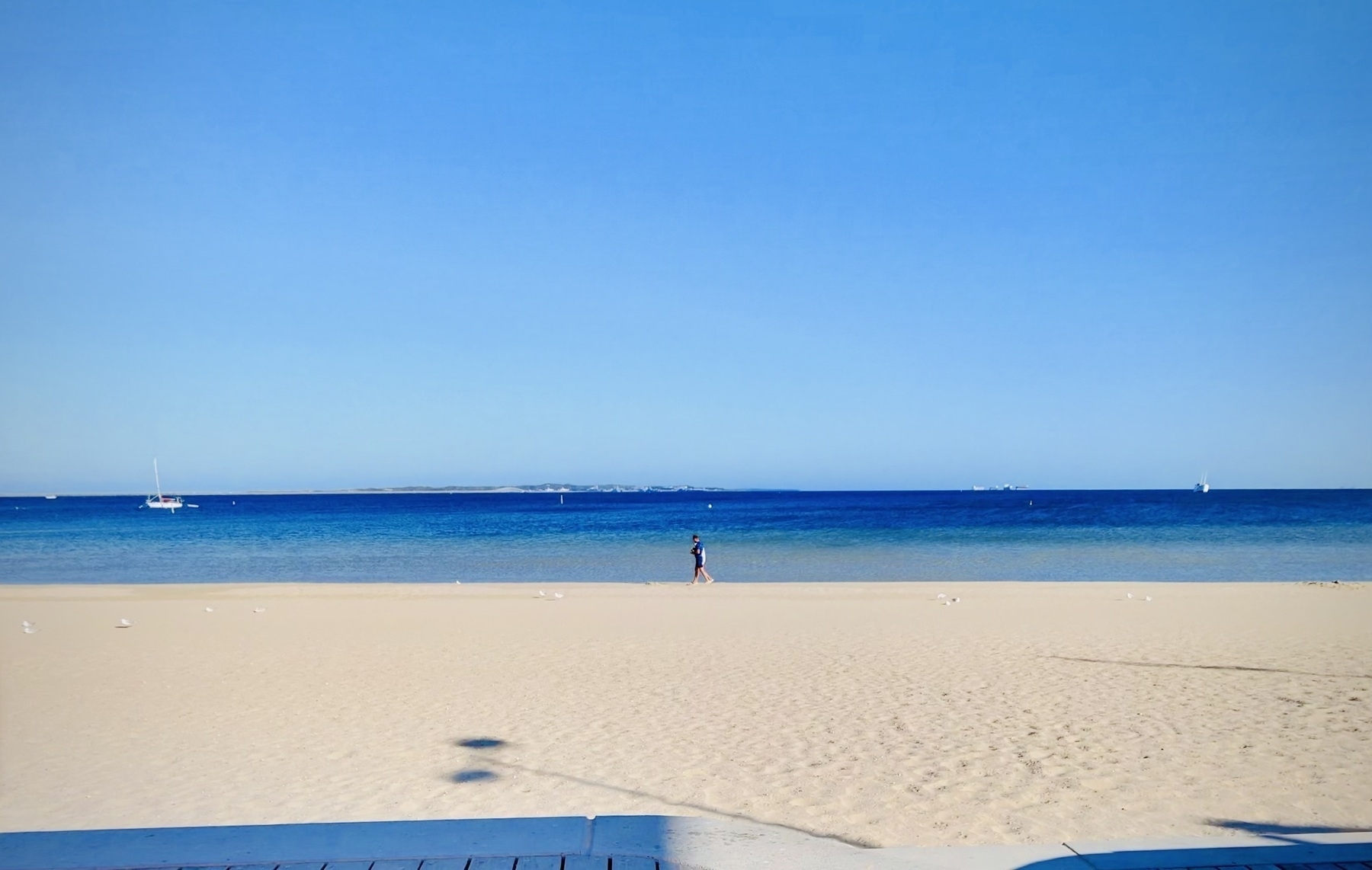 photo of someone walking along a beach with a clear blue sky - image by author