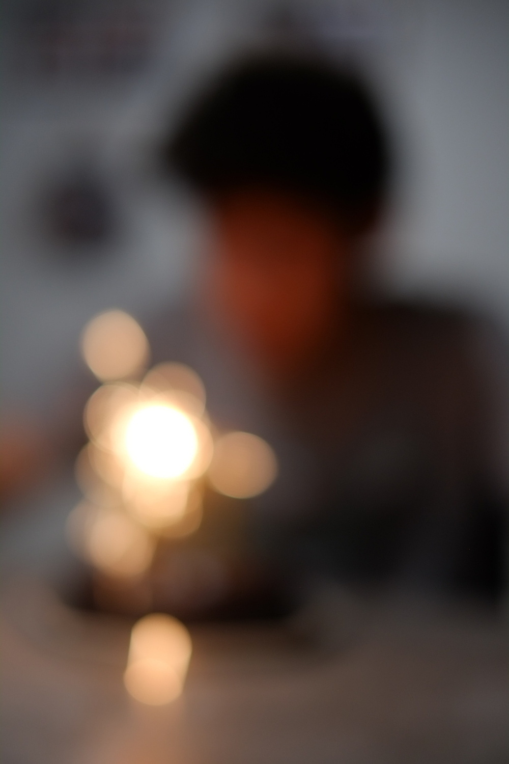 A blurred image features a warm, glowing light in the foreground with an indistinct figure in the background.