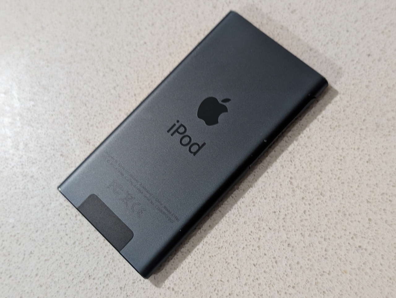 Auto-generated description: A black iPod with the Apple logo is placed on a light-colored surface.