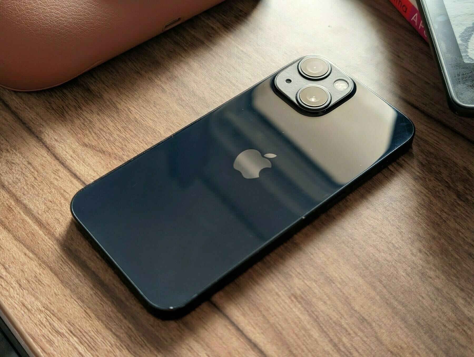 Auto-generated description: A black iPhone with dual camera lenses is placed on a wooden surface.