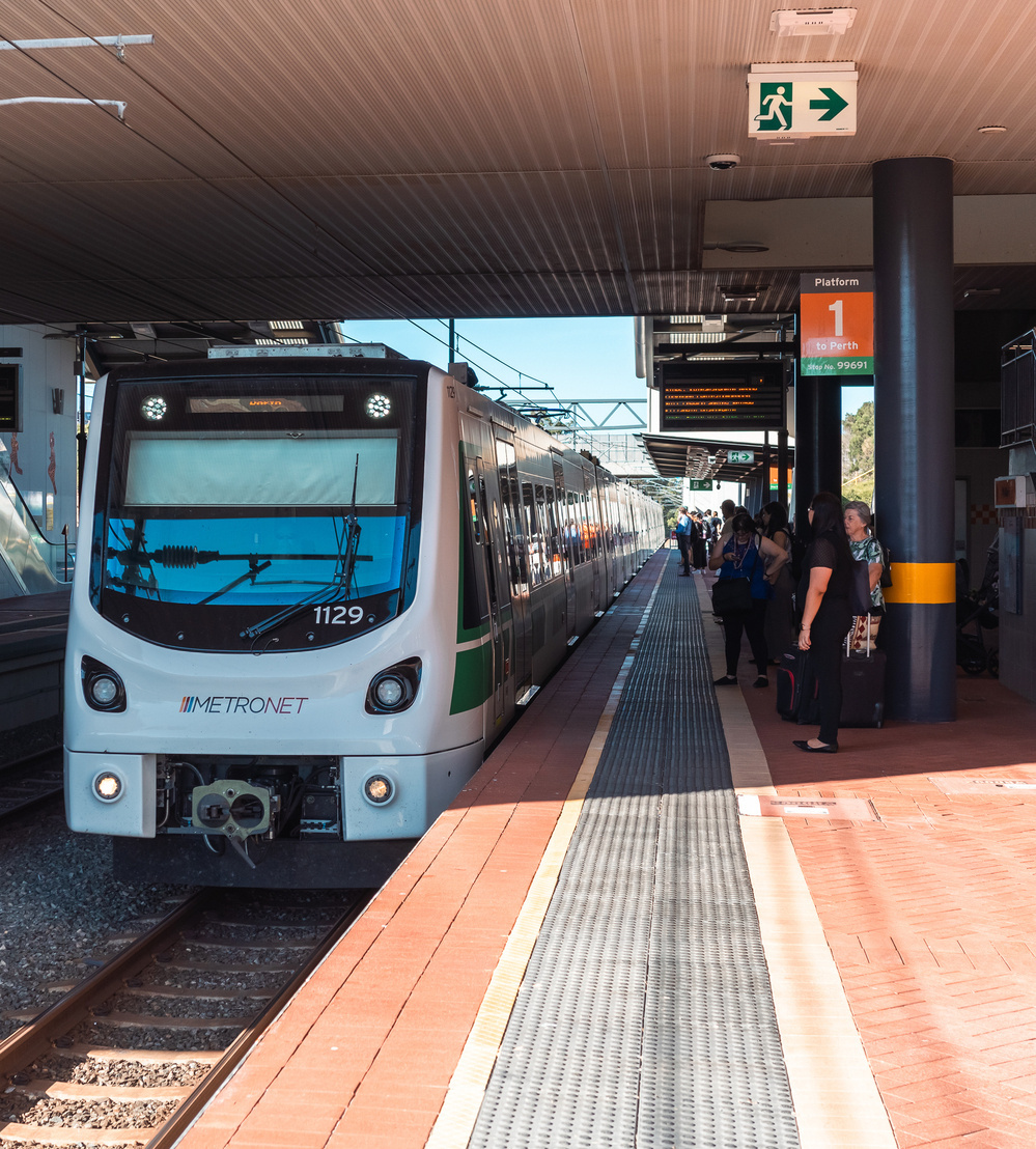 A train is stopped at a platform where people are waiting to board.