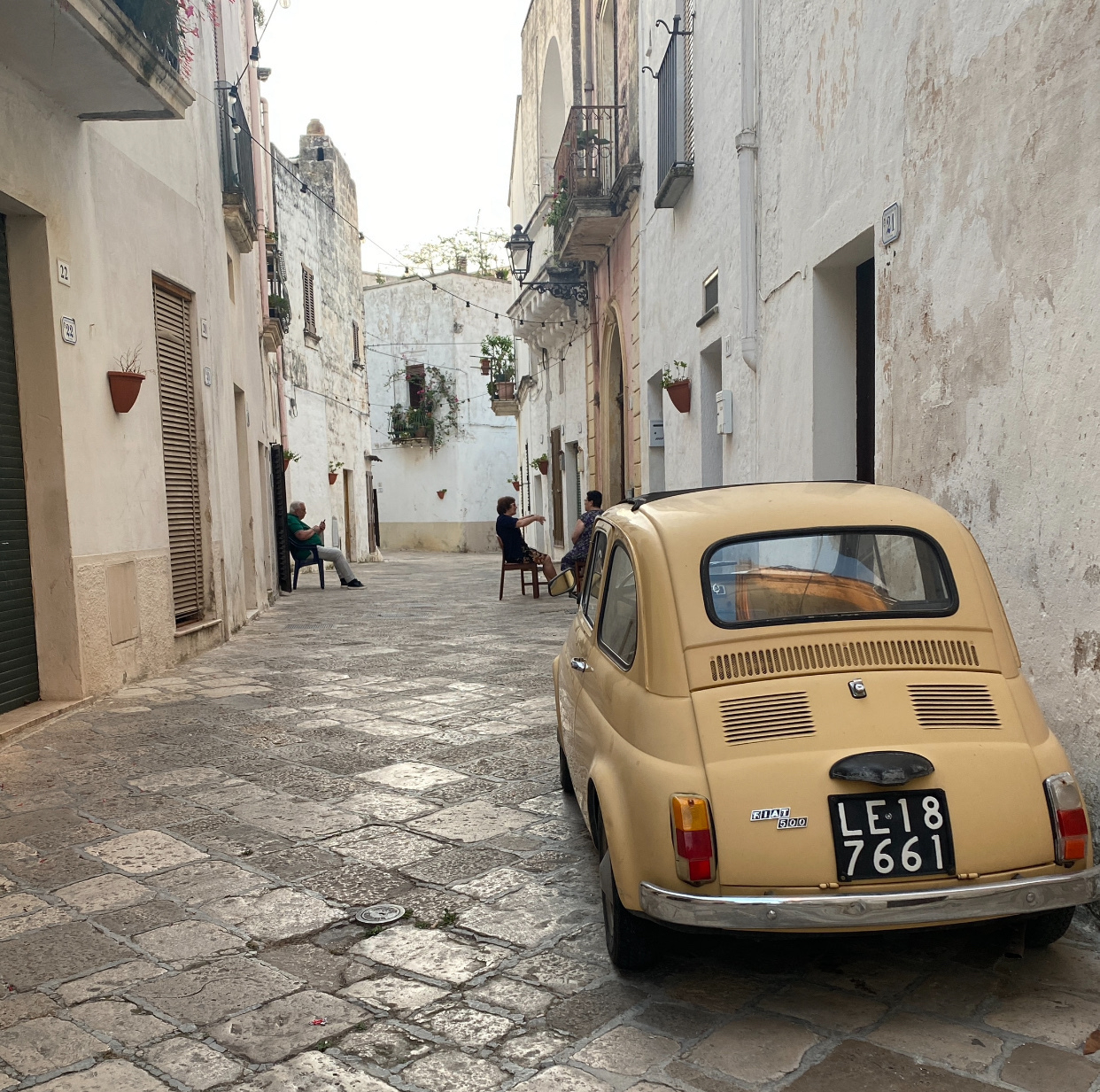 Vintage Fiat 500 sitting still on a cobbled Italian street.