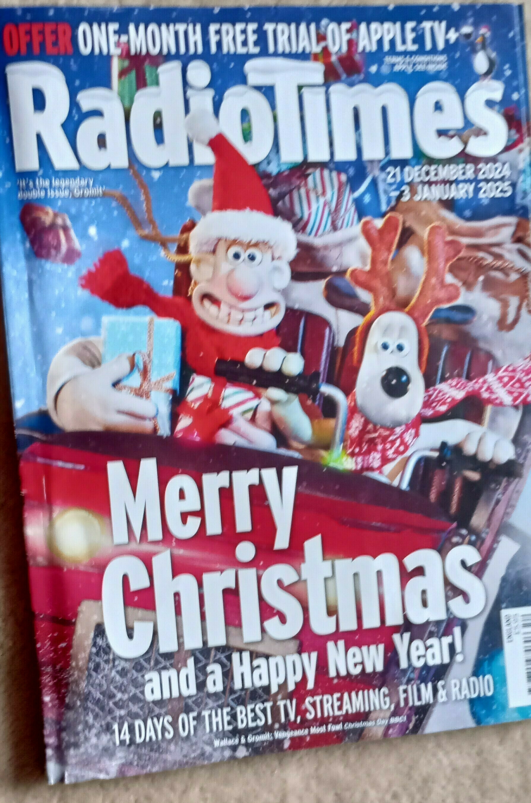 A festive magazine cover features clay characters in a Christmas setting promoting holiday TV specials.