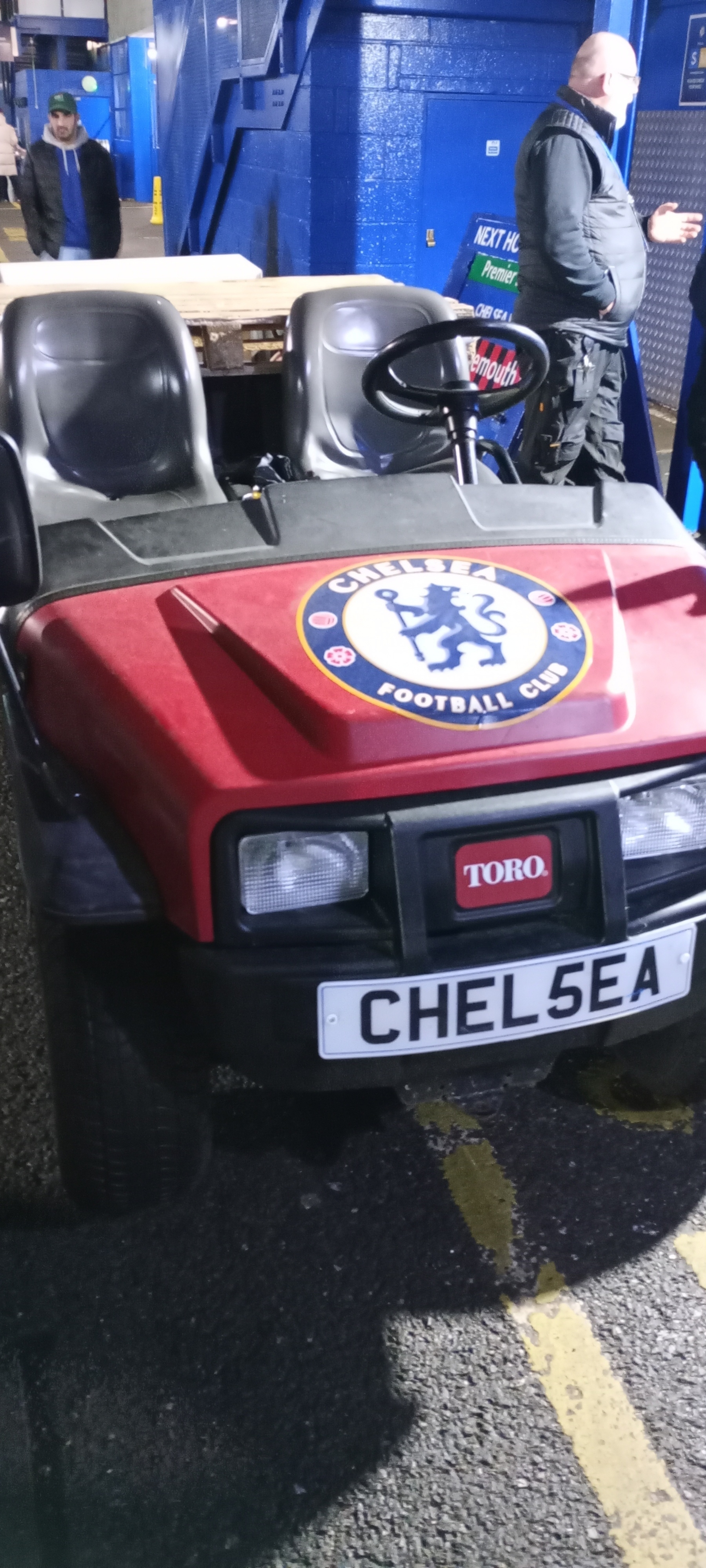 A small vehicle with a Chelsea Football Club logo on the hood is parked near a building.