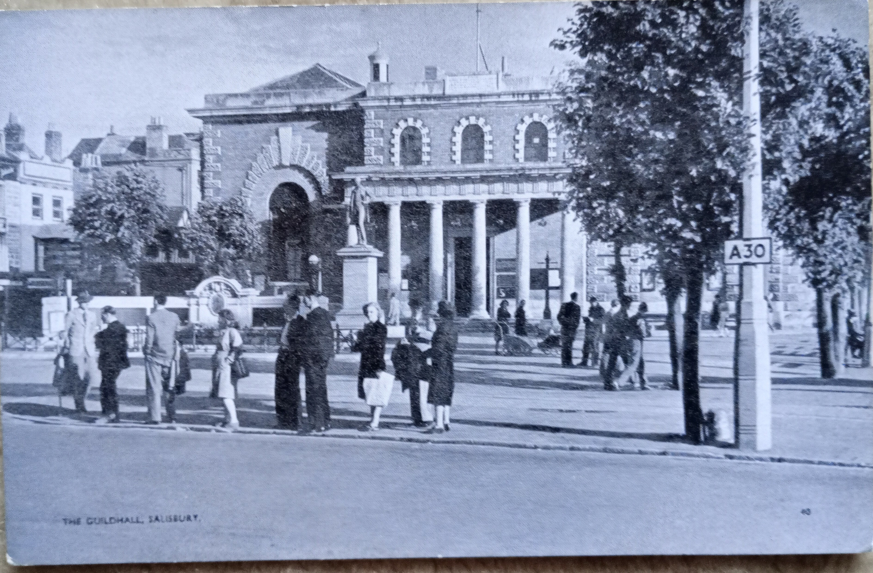 A historic building in Salisbury, labeled as the Guildhall, is depicted with people gathered and trees in the surroundings.