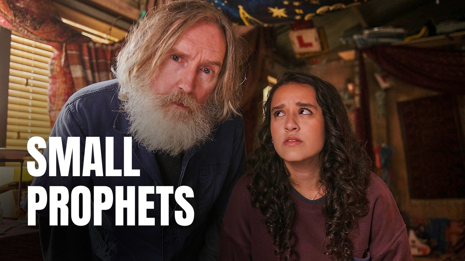 A bearded man and a young woman are in a room with cluttered decor, accompanied by the text Small Prophets.