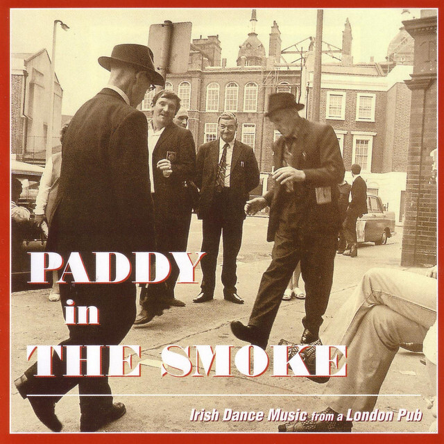 People in hats and suits gather on a street corner, evoking a vintage scene, with the text Paddy in the Smoke and Irish Dance Music from a London Pub overlaid.