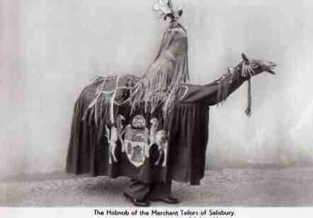 A person is dressed in a decorated costume resembling a rider on a horse-like creature, covered with ornate fabric and tassels.