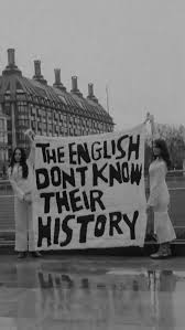 Auto-generated description: Two people are holding a banner that reads THE ENGLISH DON'T KNOW THEIR HISTORY in front of a large building.