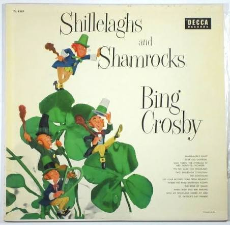 Four leprechauns are playfully interacting with giant shamrocks on an album cover titled Shillelaghs and Shamrocks by Bing Crosby.