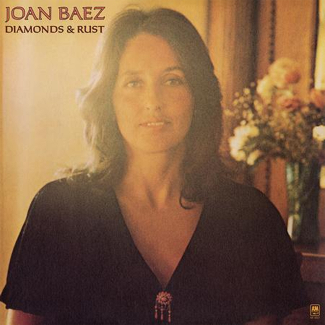 A person stands in front of a blurred background with flowers, on an album cover labeled Joan Baez Diamonds & Rust.