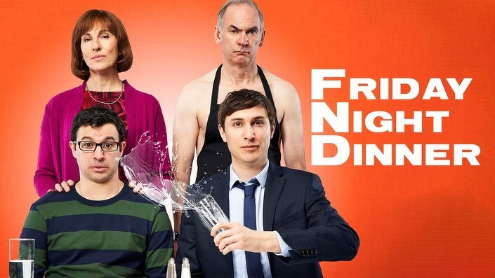 Four people, including a man in a suit holding a broken glass, are posed in front of an orange background with the text Friday Night Dinner.