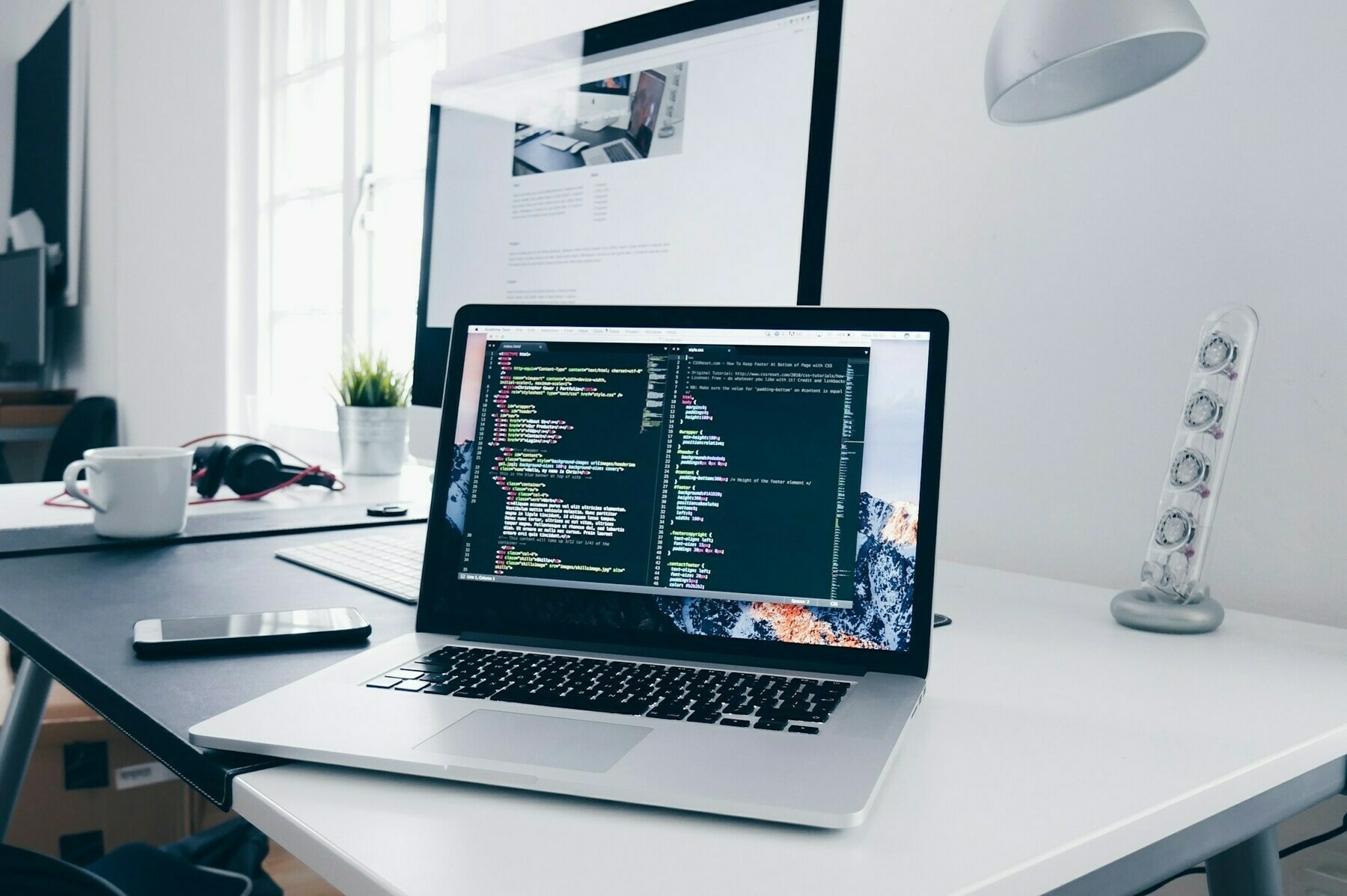 A laptop on a desk showing code on the screen