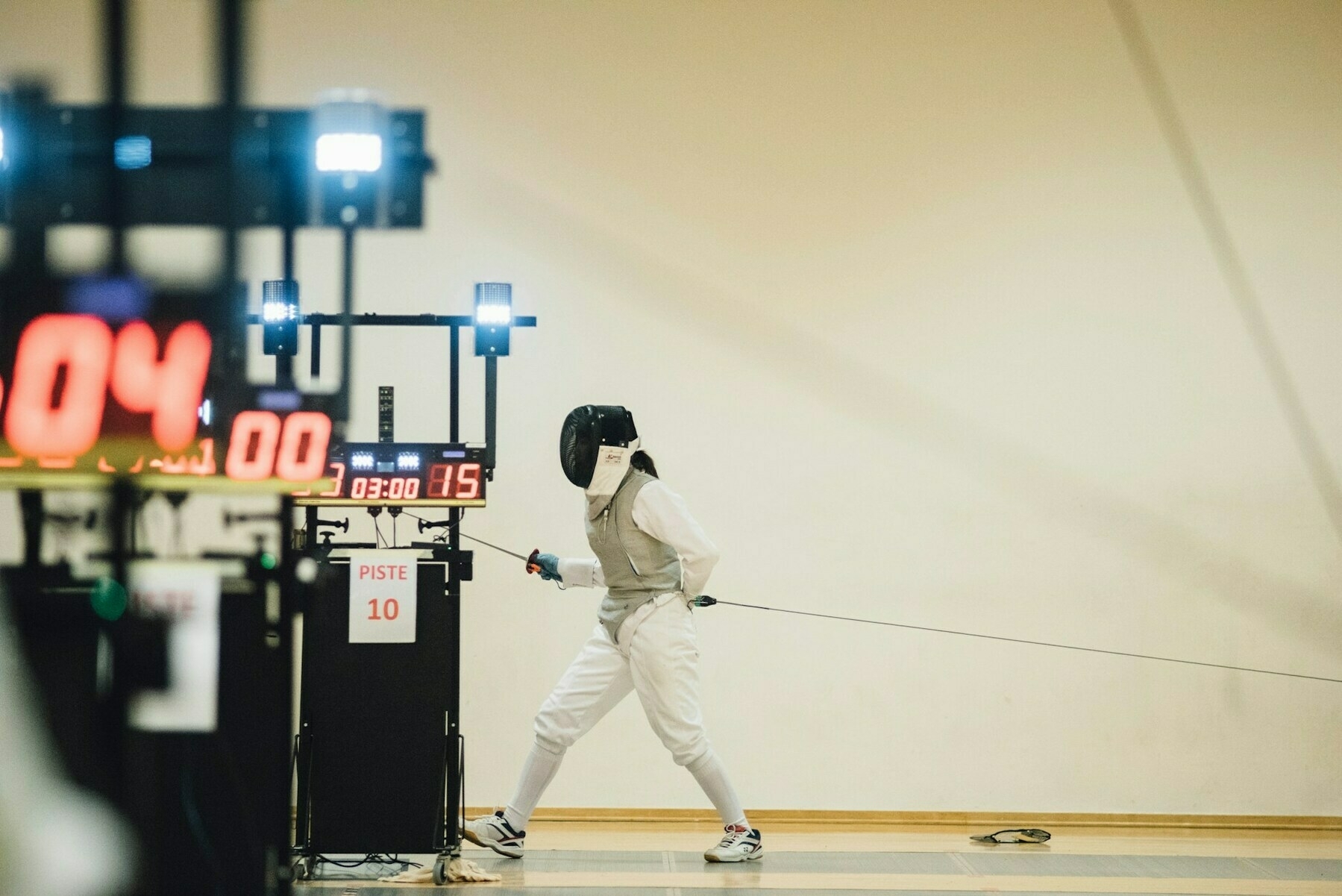 Fencer standing near white painted wall