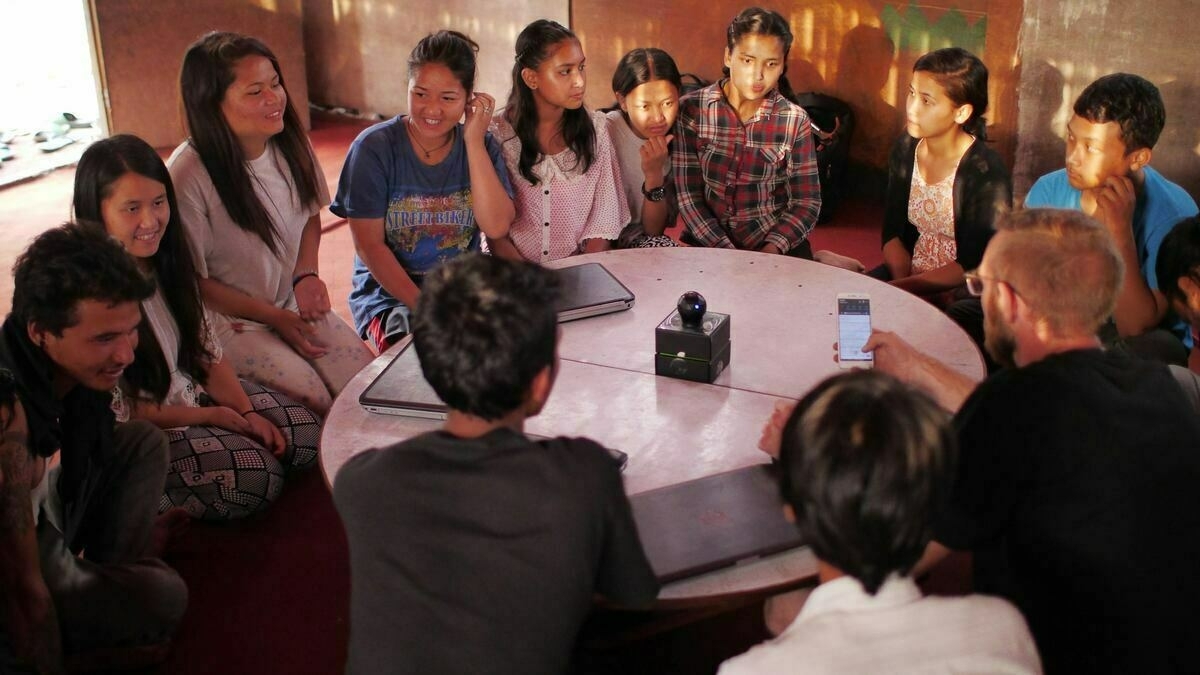 People sitting on the floor round a table. 