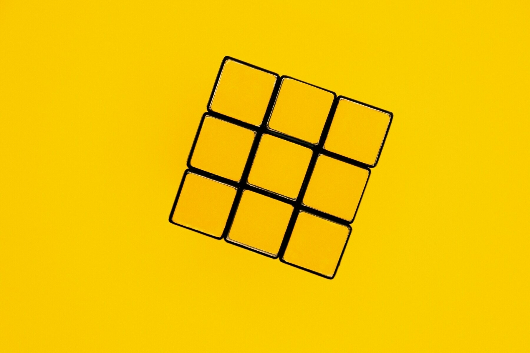Yellow side of a solved Rubik's cube on a yellow background