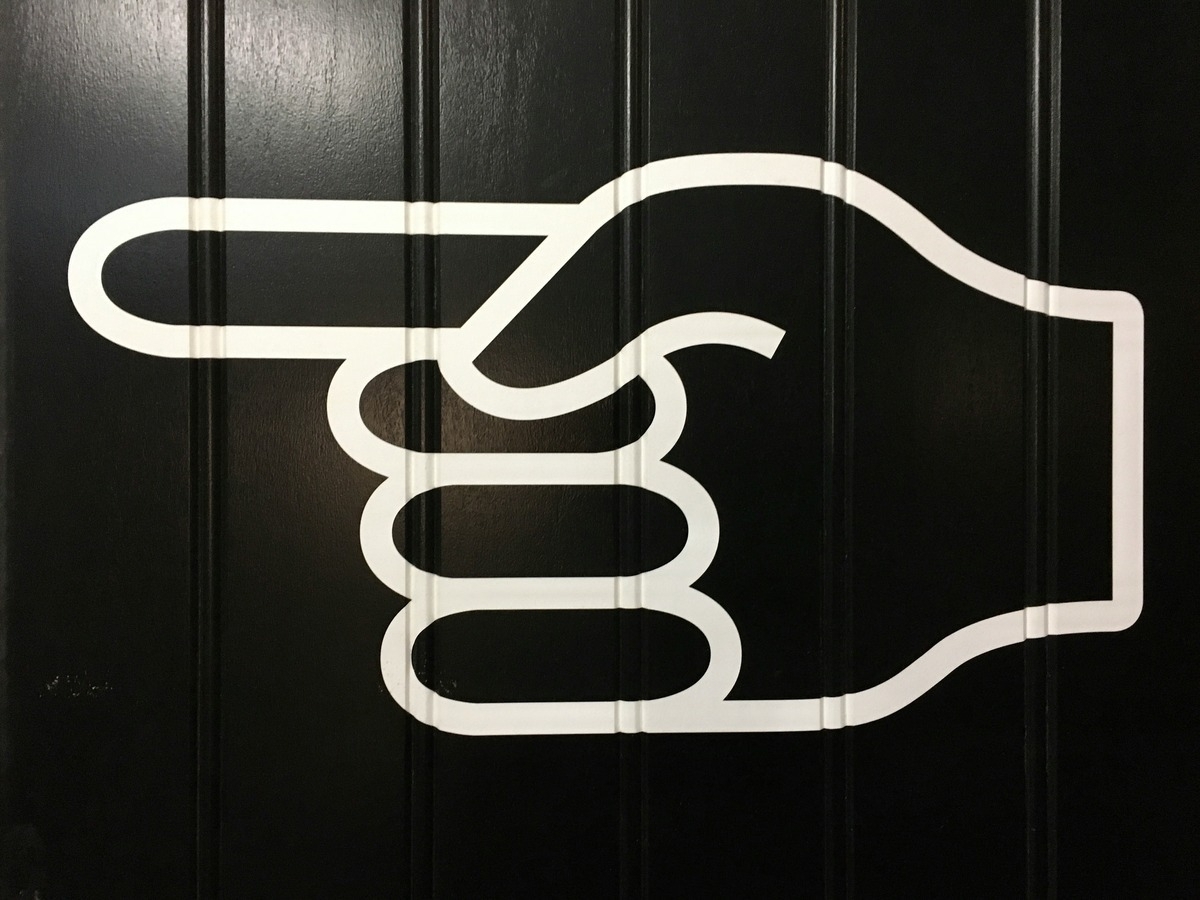 Black background with stylised white-outlined hand pointing to the left