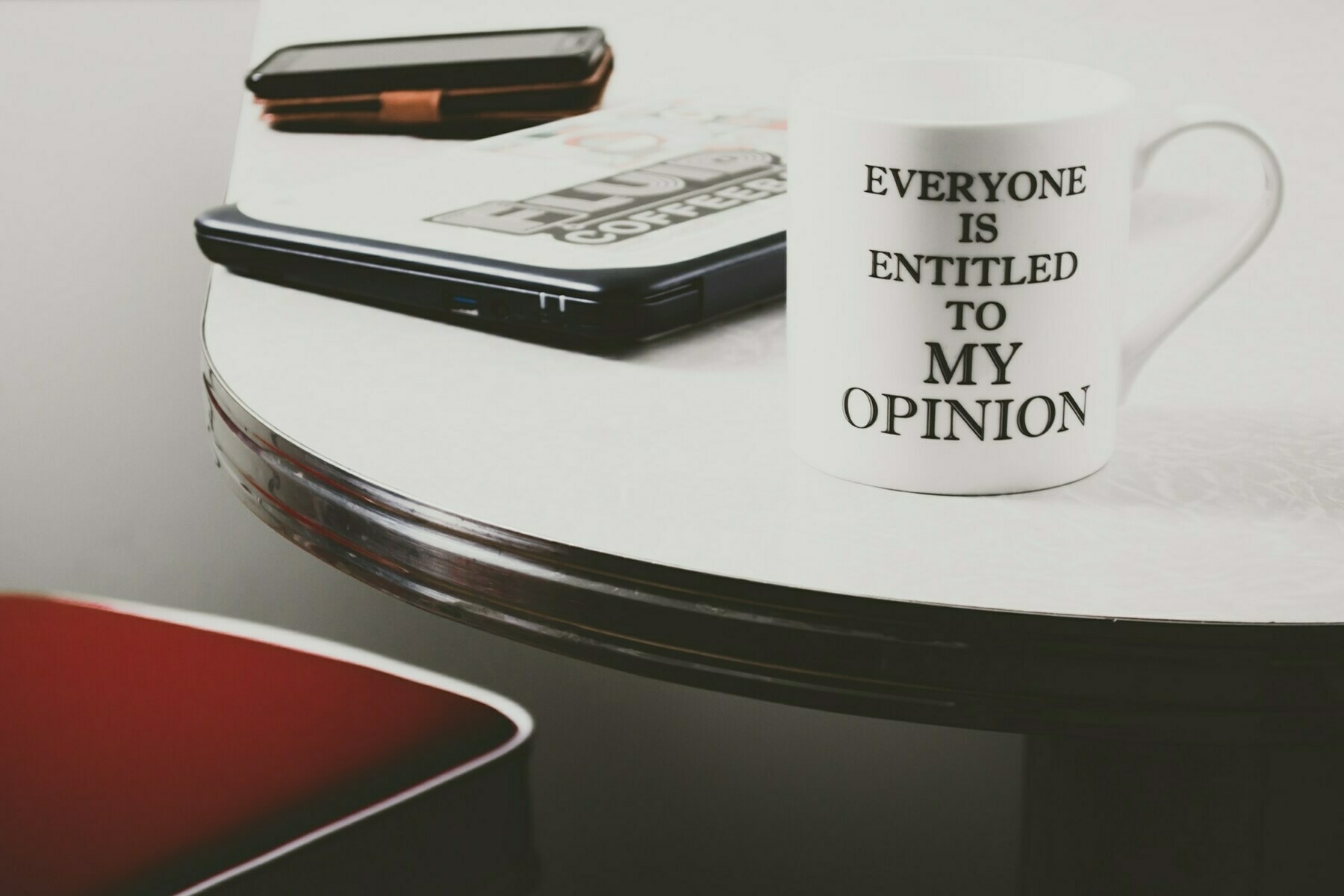 Mug on desk with writing on it which reads: 'Everyone is entitled to my opinion'