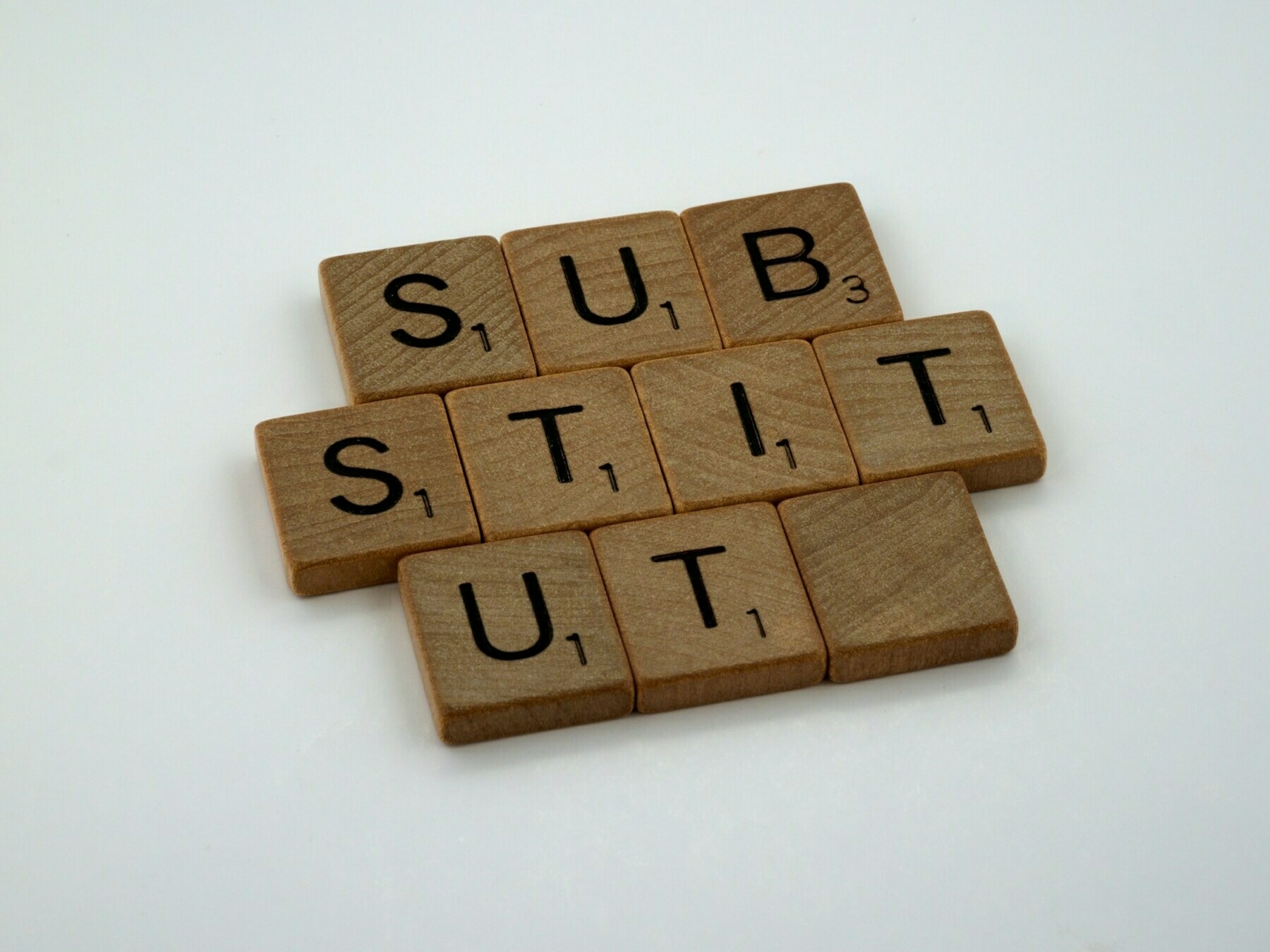 Scrabble letters spelling out the word 'SUBSTITUTE' with the letter 'E' replaced by a blank