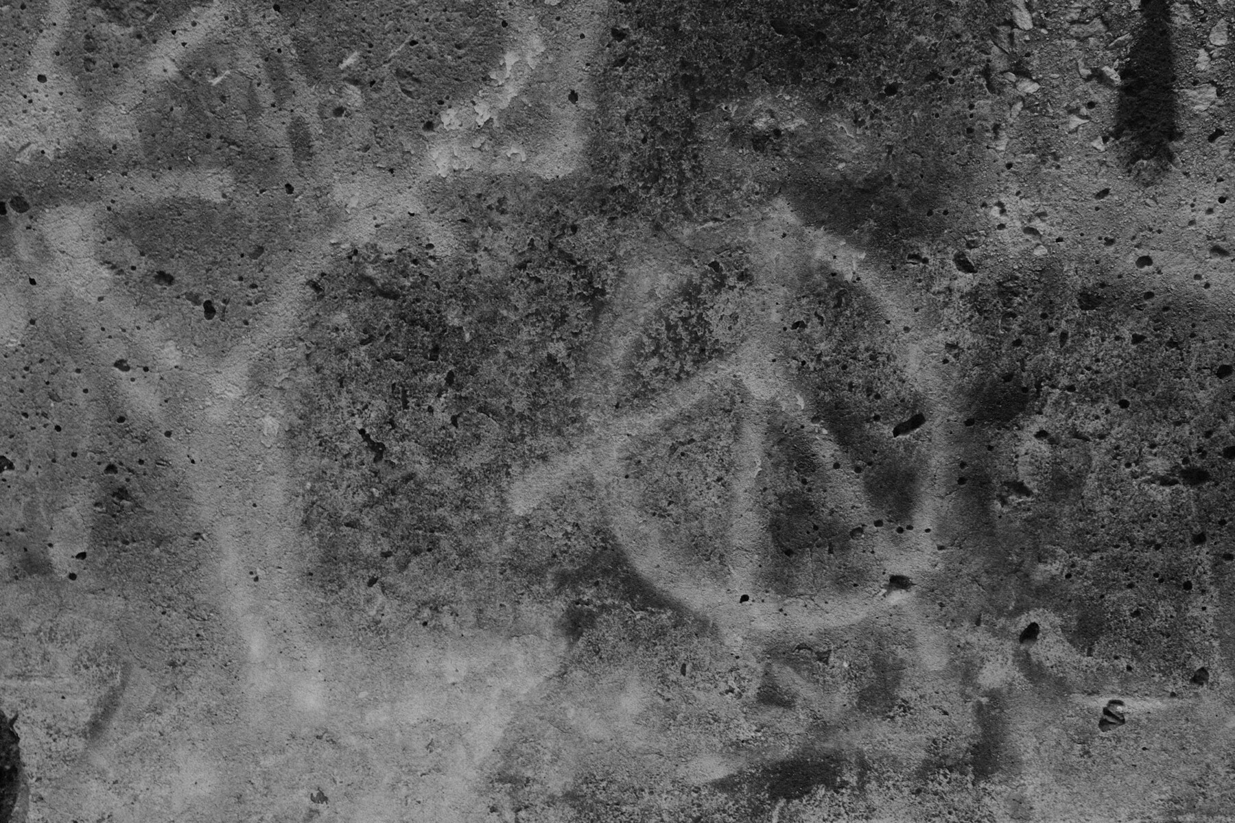Auto-generated description: A weathered concrete wall features a peace symbol graffiti sketch.