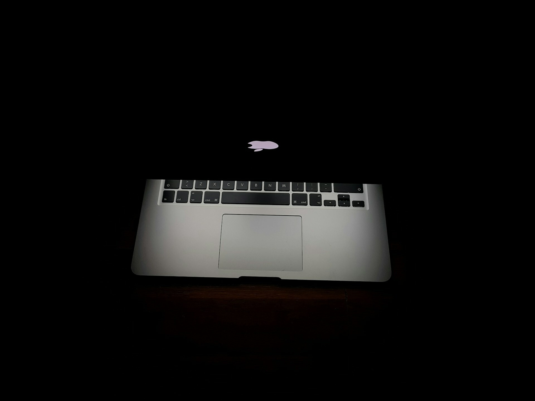 Partly-closed MacBook with black background