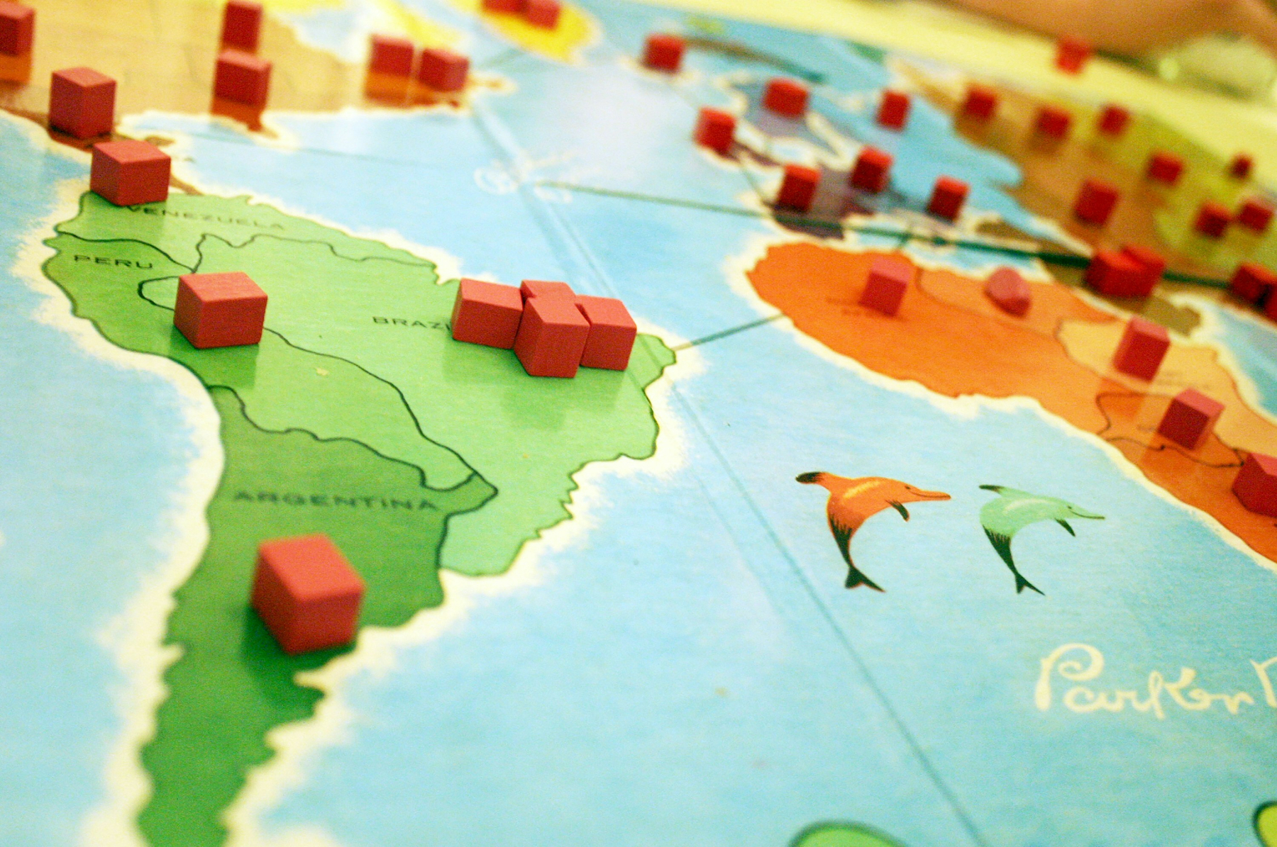 Auto-generated description: A board game map of South America with red cubes placed on various locations.