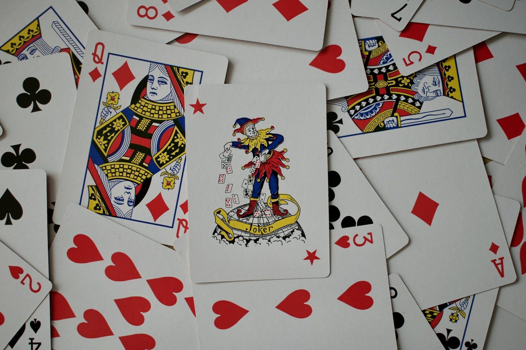 Auto-generated description: A variety of playing cards, including a joker, are scattered randomly.