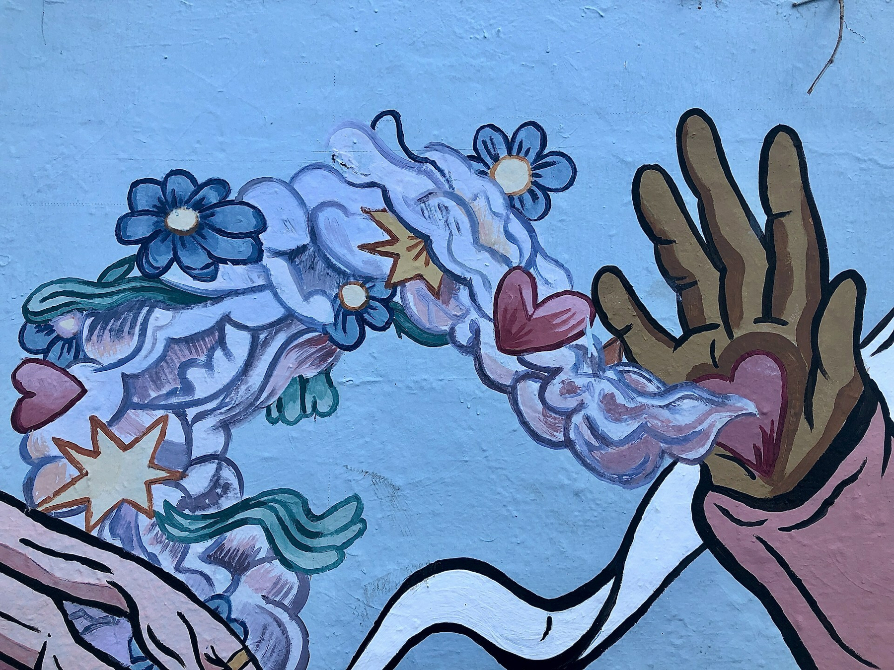 Auto-generated description: A mural depicts a hand releasing a colorful swirl of flowers, hearts, and abstract shapes.