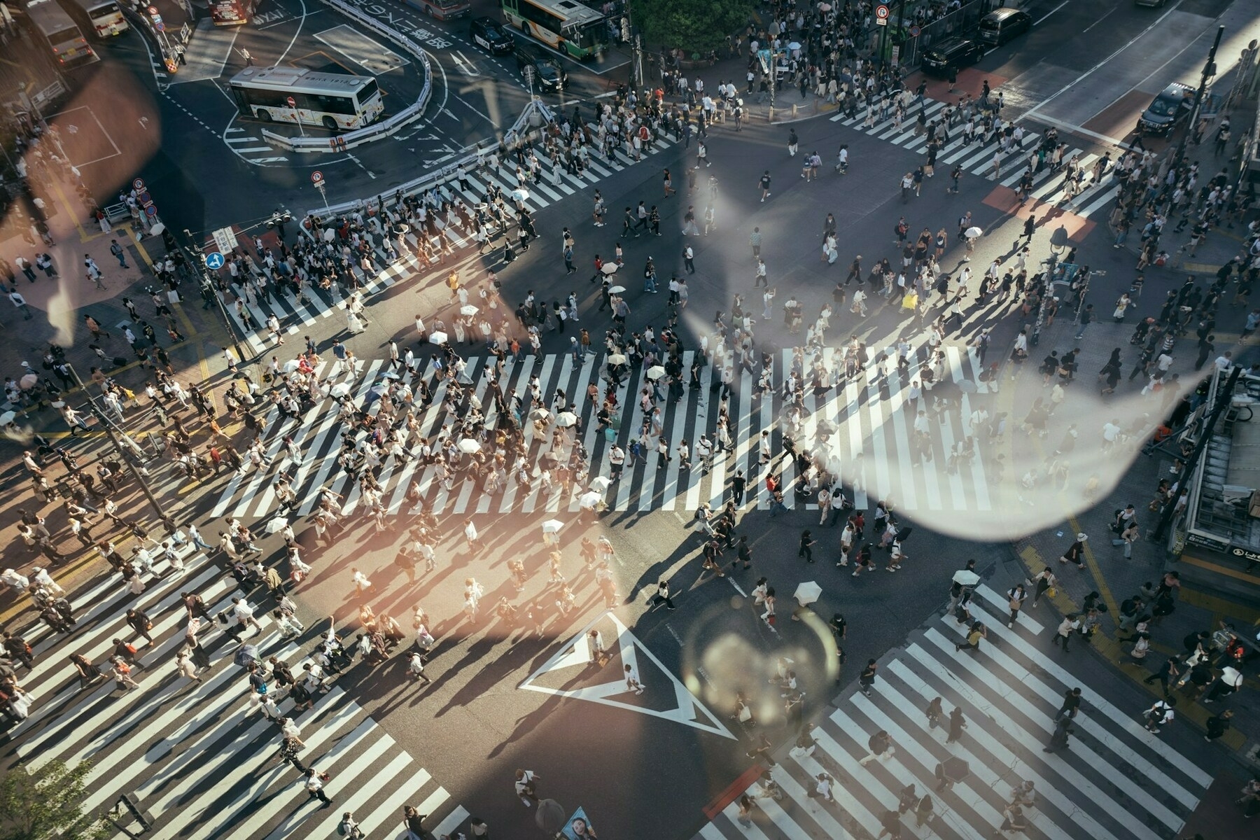 Auto-generated description: A bustling city intersection is filled with numerous people crossing the street, surrounded by multiple pedestrian crosswalks.