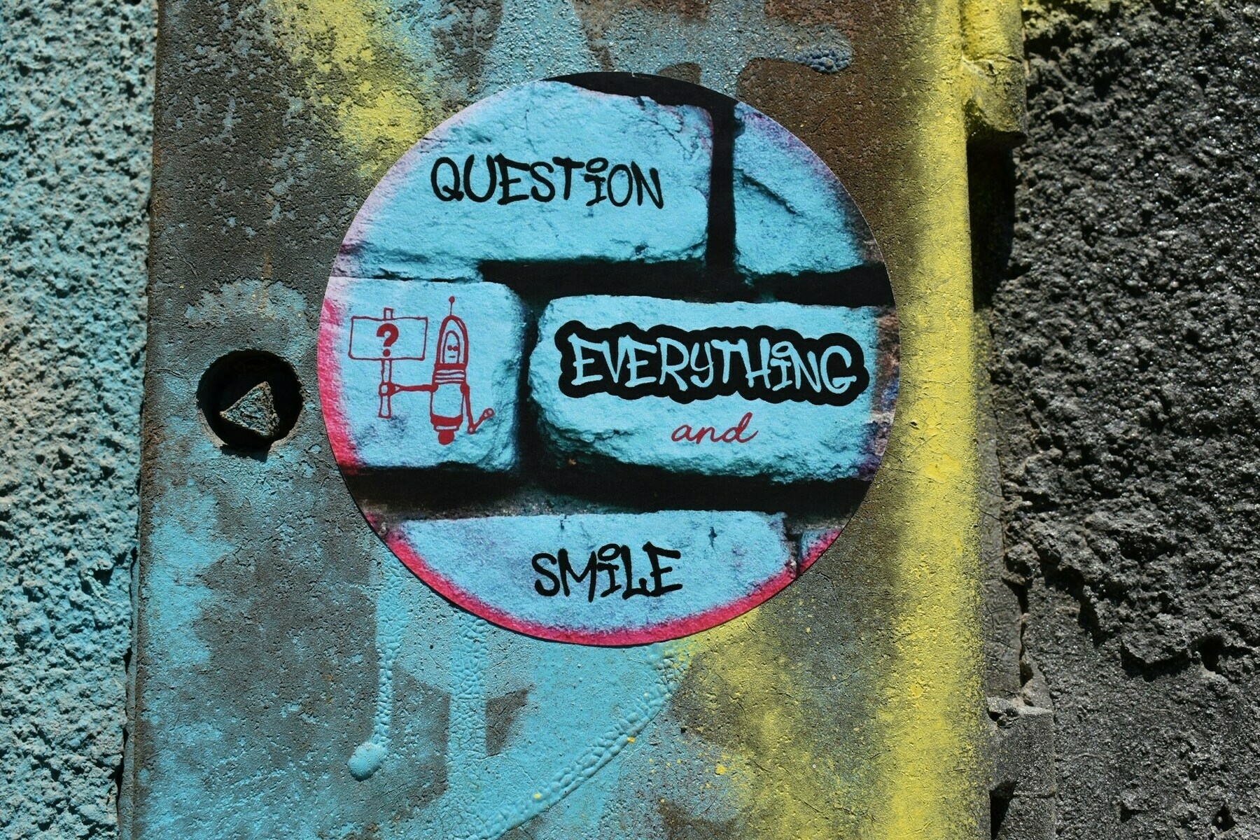 a painted sign on a wall that says question everything and smile