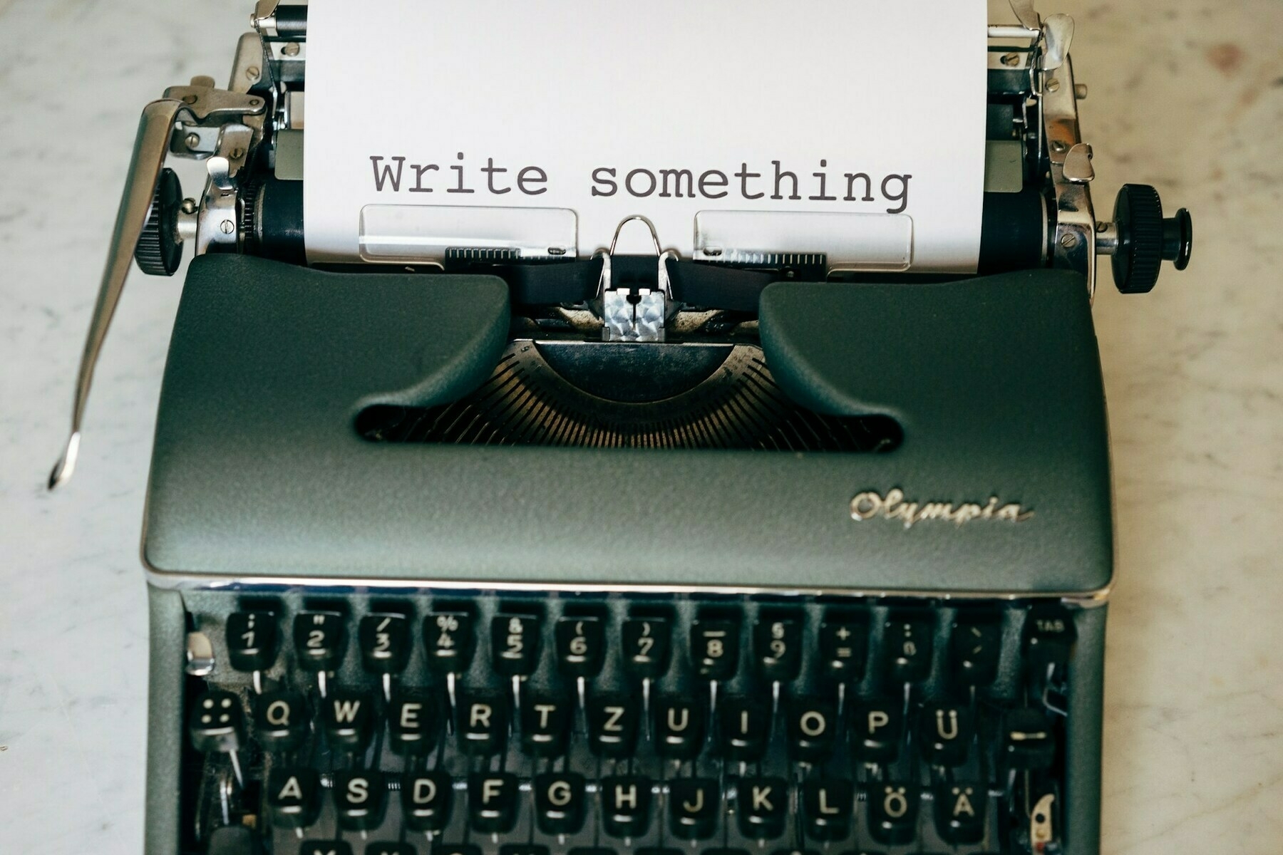 Green typewriter with paper that says WRITE SOMETHING