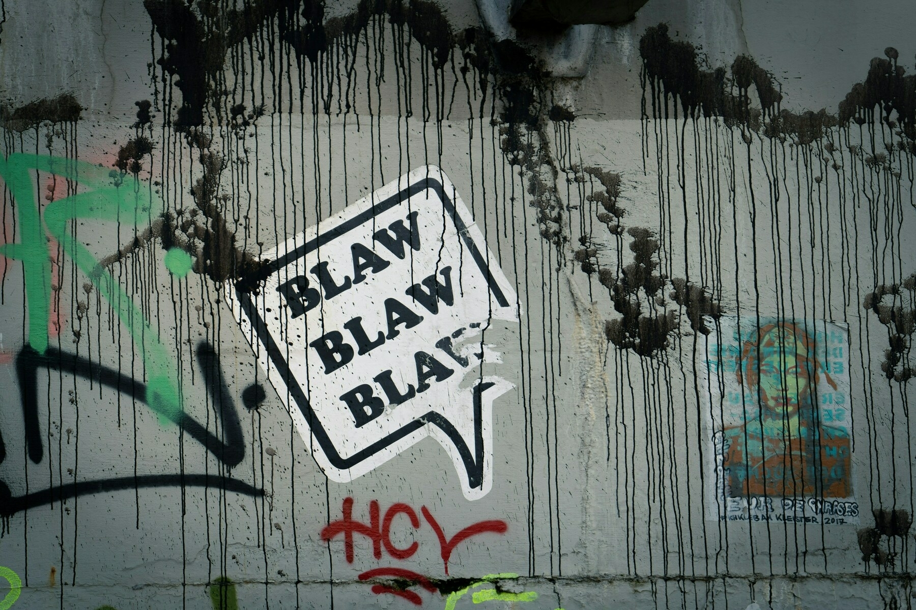 Auto-generated description: A graffiti-covered wall features a speech bubble sticker saying BLAW BLAW BLAW and other colorful tags.