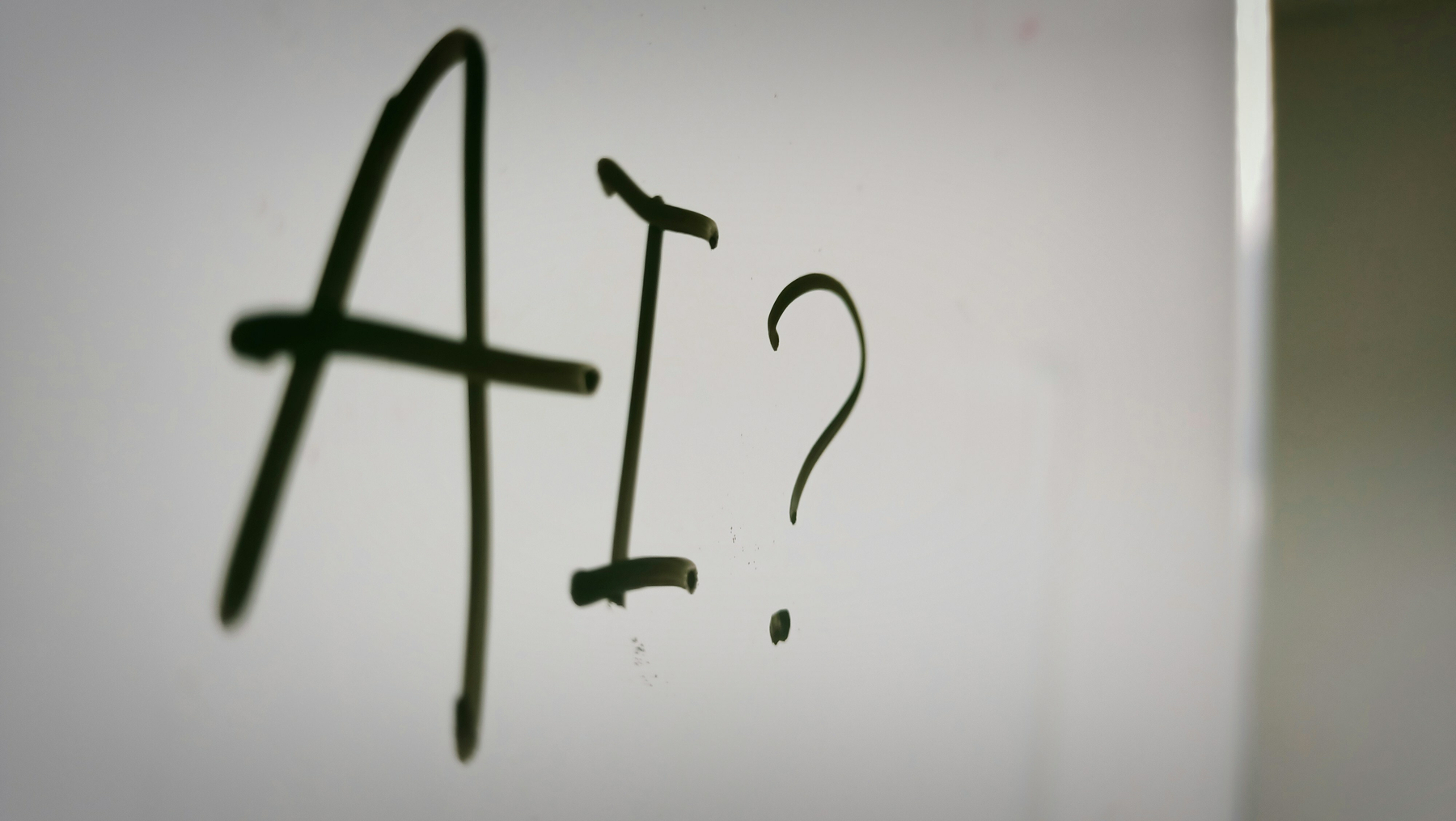 Auto-generated description: The text 'AI?' is written on a whiteboard or similar surface.