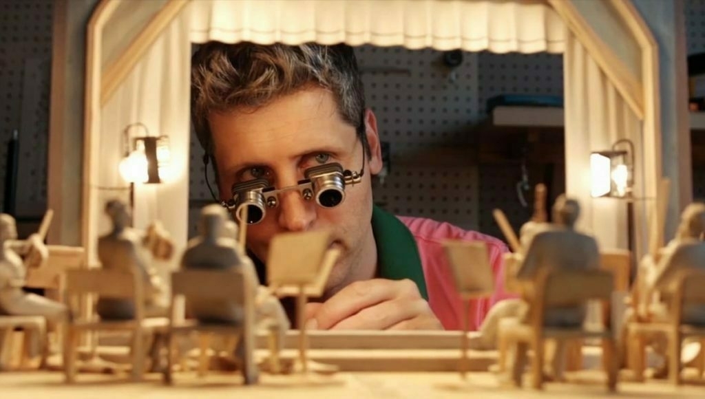 AI-generated image of Sam Altman wearing magnifying lenses while creating a miniature theatre scene