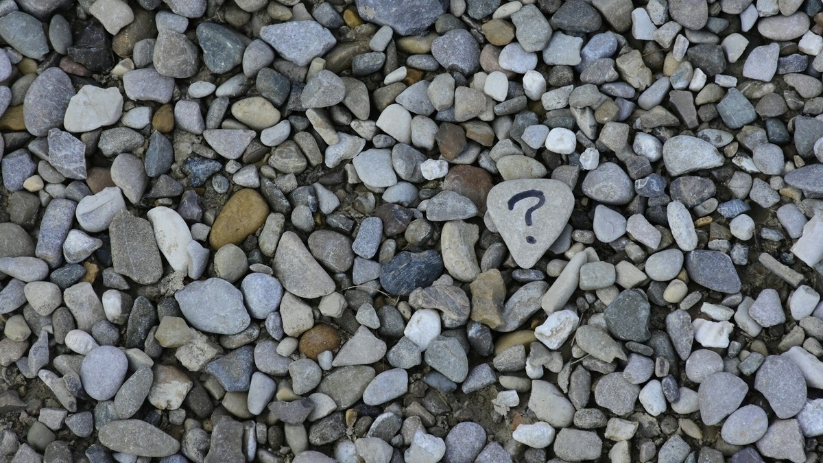 Pebbles with a stone featuring a question mark.