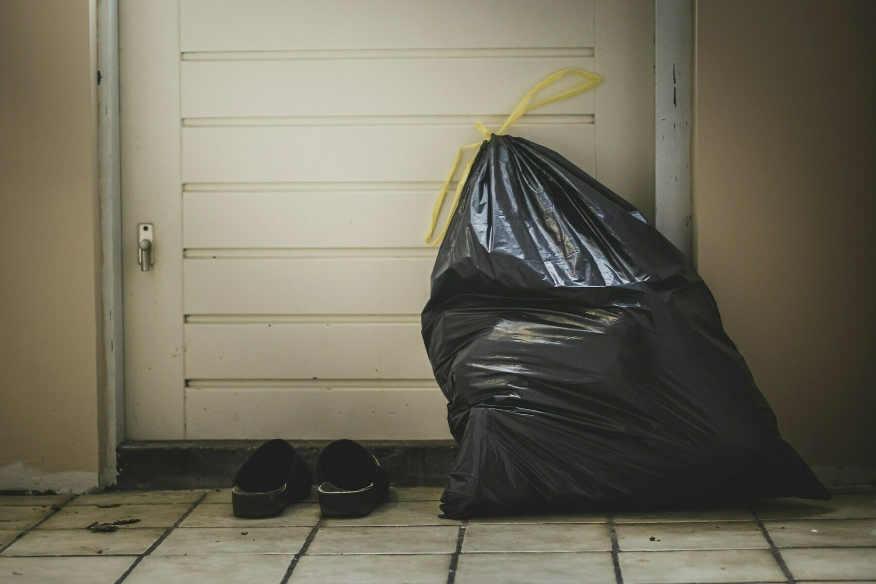 Bin bag and slippers next to a door