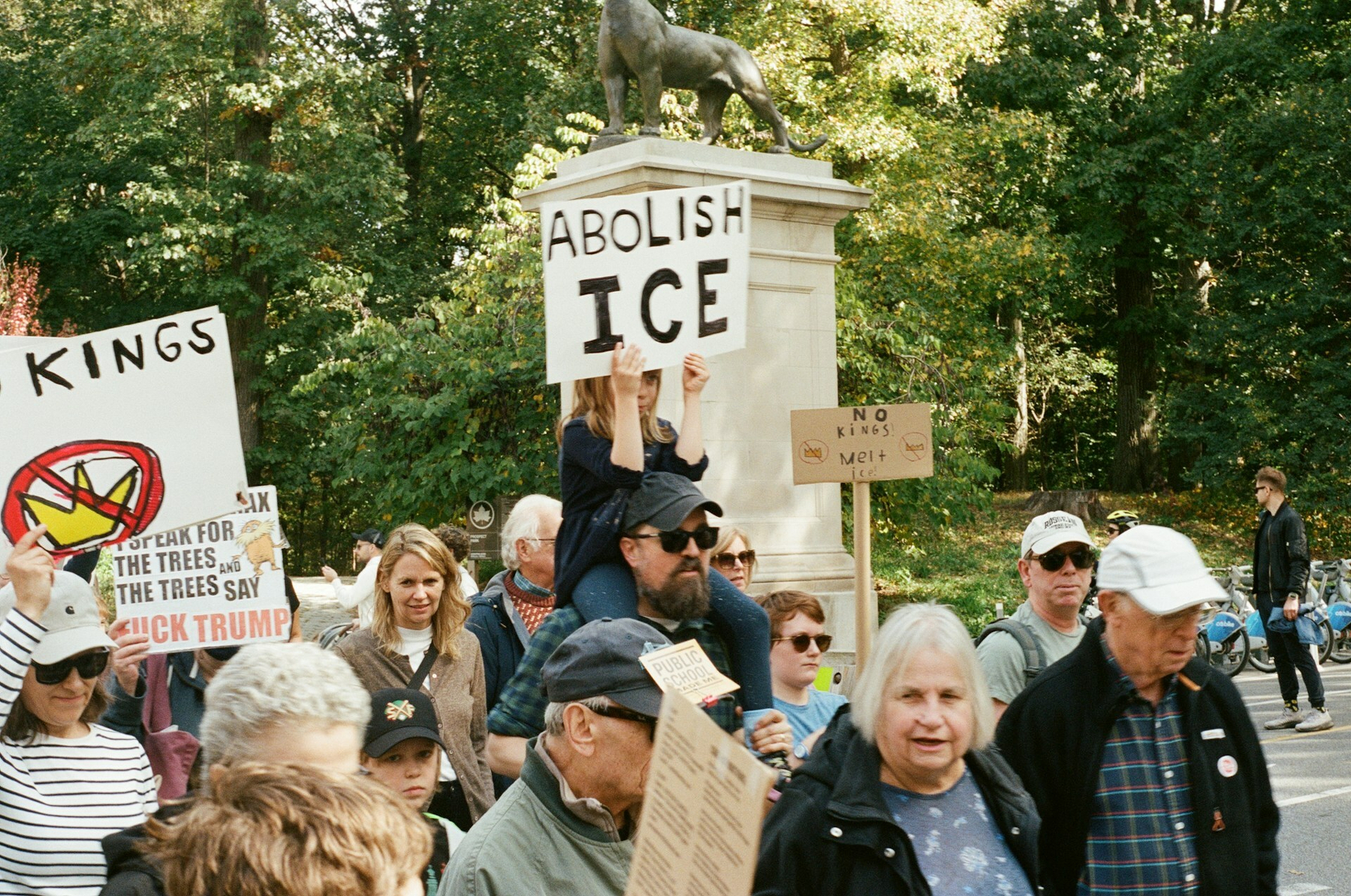 Auto-generated description: A group of people are participating in a protest holding signs with various political messages, including Abolish ICE.